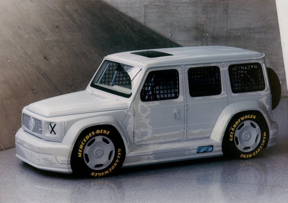 Project Geländewagen by Virgil Abloh, a hand-sanded matte-white lowered and widened Mercedes-Benz G-Class art car with yellow racing tyre lettering, front three-quarter view